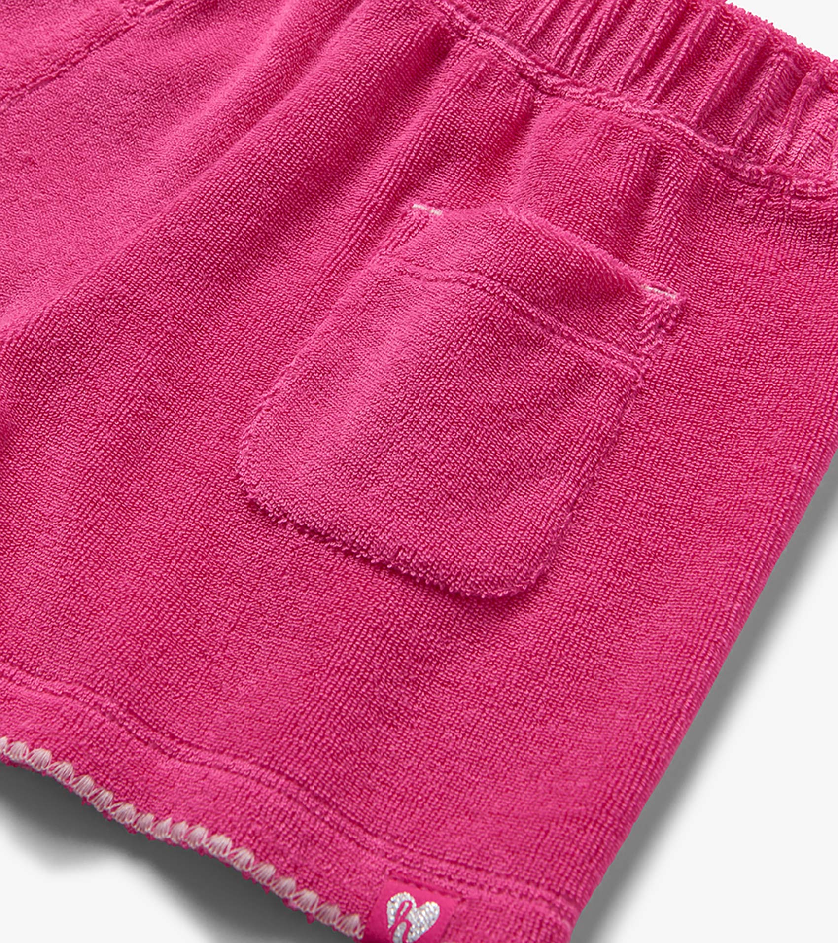Pink textured knit shorts with elastic waistband and back pocket, close-up view