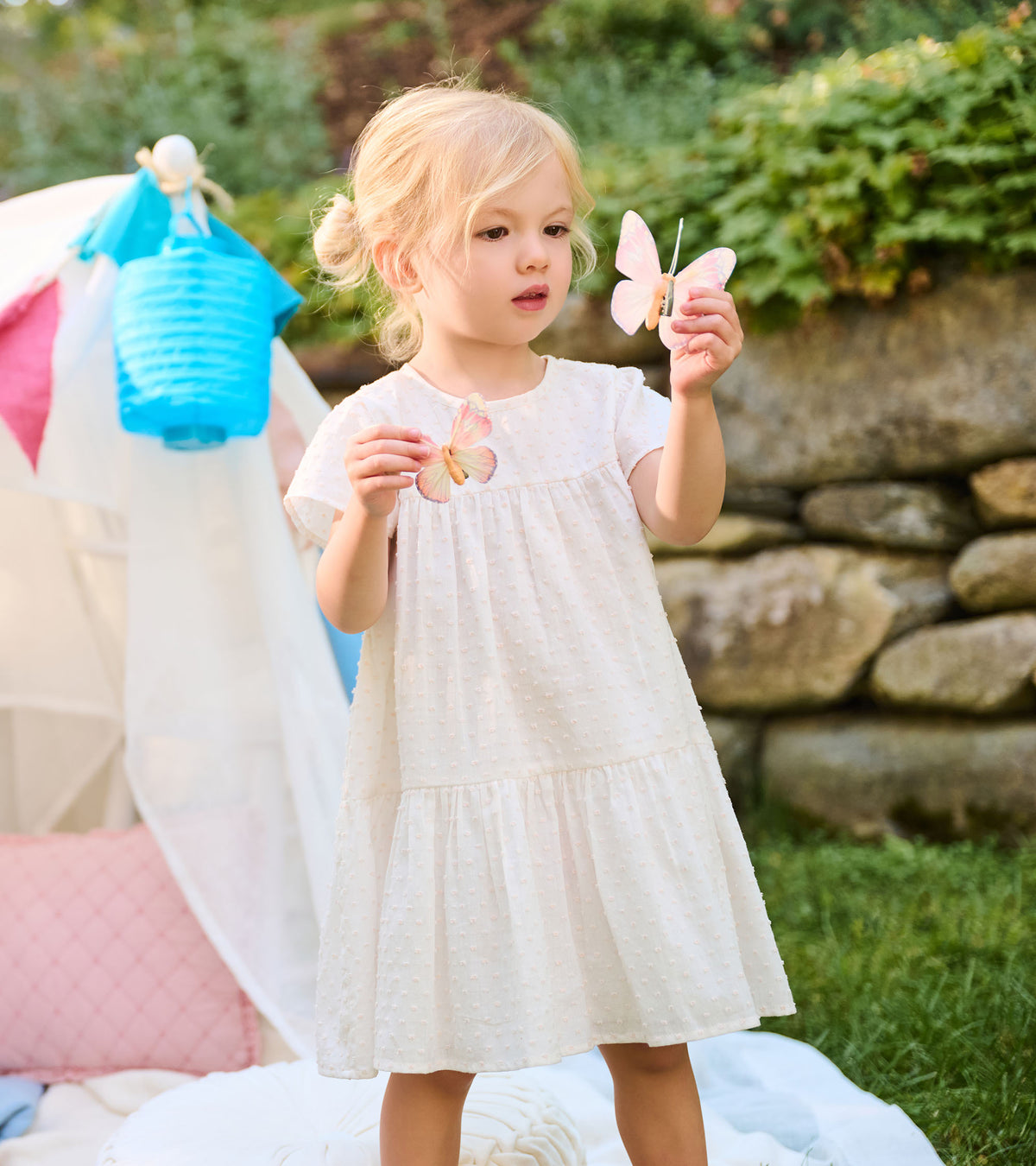 Toddler wearing pearl Swiss dot dress, shown closer with short sleeves and tiered skirt