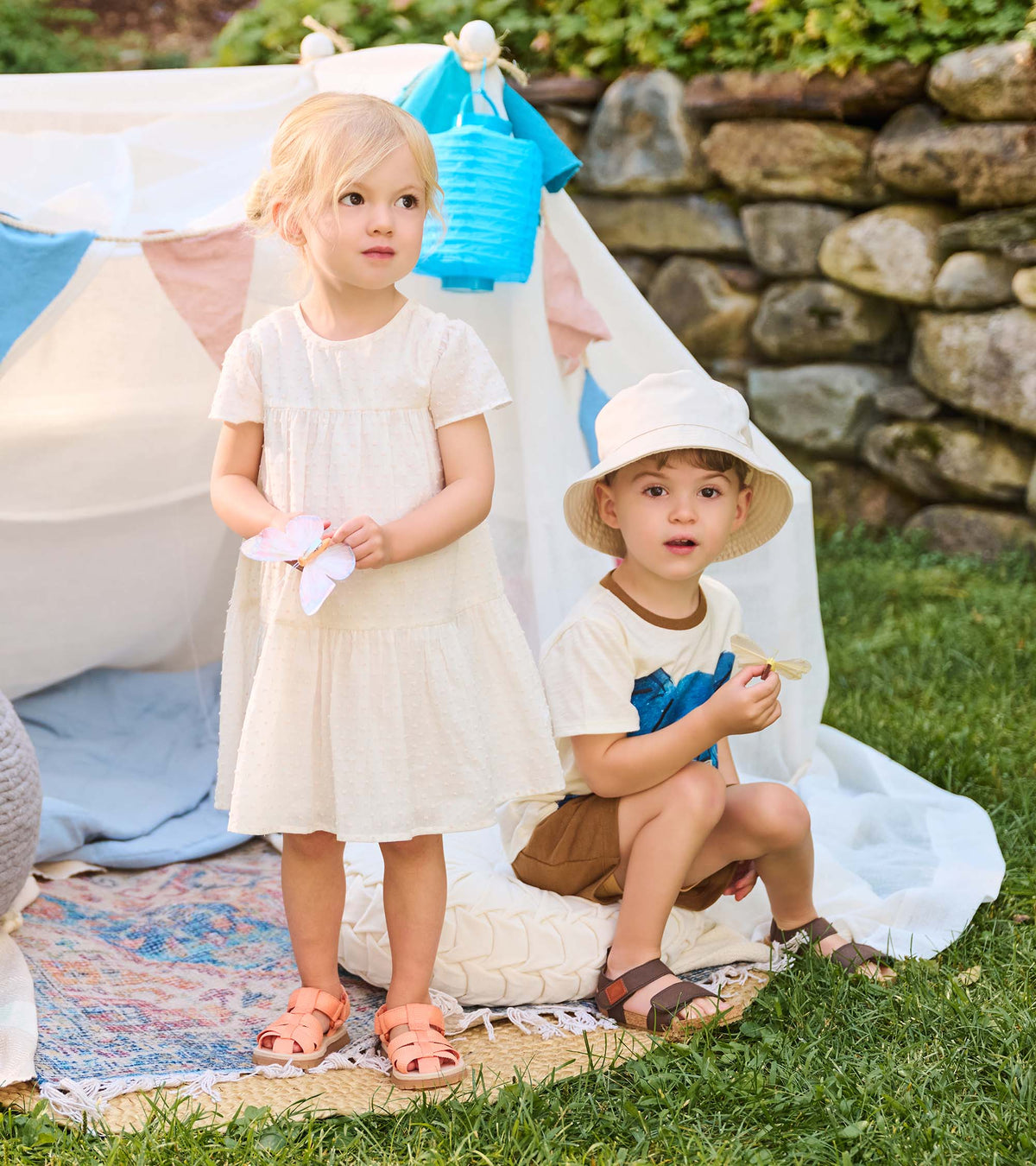 Toddler in pearl Swiss dot dress standing outdoors beside another child