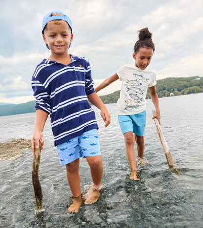 Boy wearing navy striped hooded long-sleeve cover-up with light blue shorts, standing in shallow water