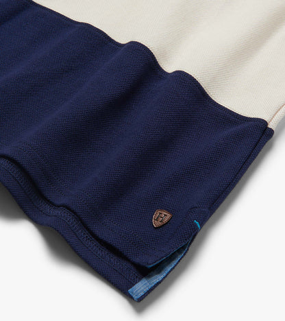 Folded navy and white color block polo shirt with textured knit fabric and small chest logo patch