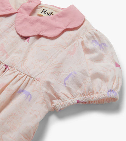 Close-up of a pale pink toddler dress with woven collar and pastel pony print, gathered sleeve cuff