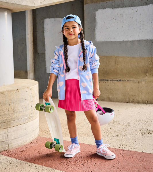 Girl wearing a light blue full-zip hoodie with pink heart print, shown open with skateboard and helmet