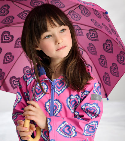 Girl wearing pink heart-pattern zip-up raincoat holding matching umbrella, front view