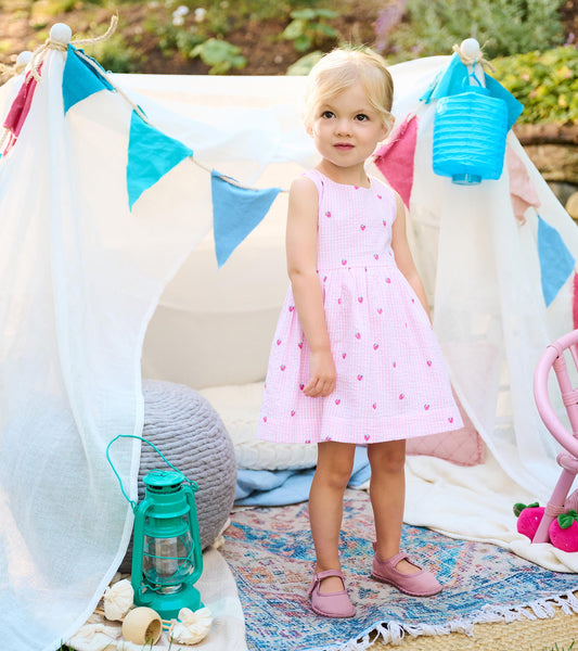 Toddler wearing a sleeveless pink gingham party dress with tiny berry motifs and a gathered skirt