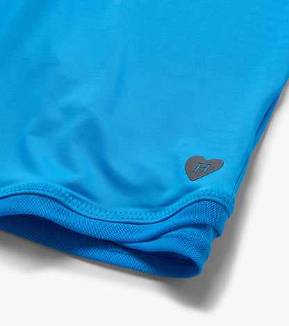 Bright blue girls' T-shirt with mesh trim and small heart logo near the hem, close-up view