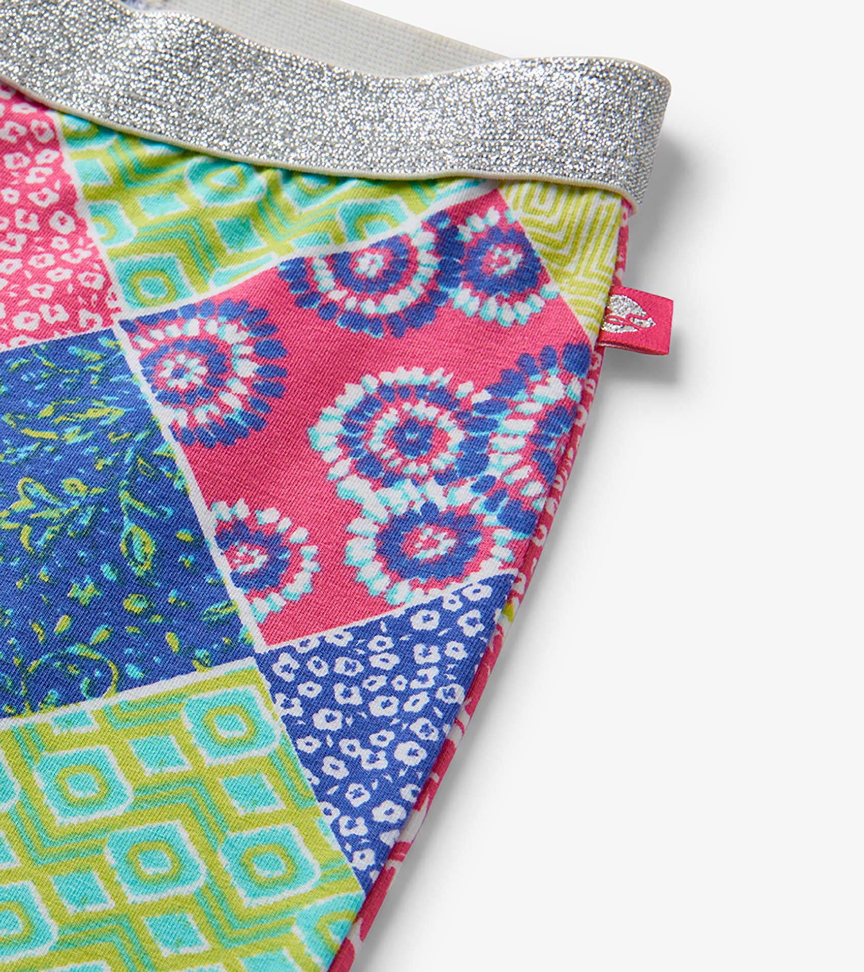 Colorful patchwork girls bell-bottom pants with silver glitter waistband, close-up detail