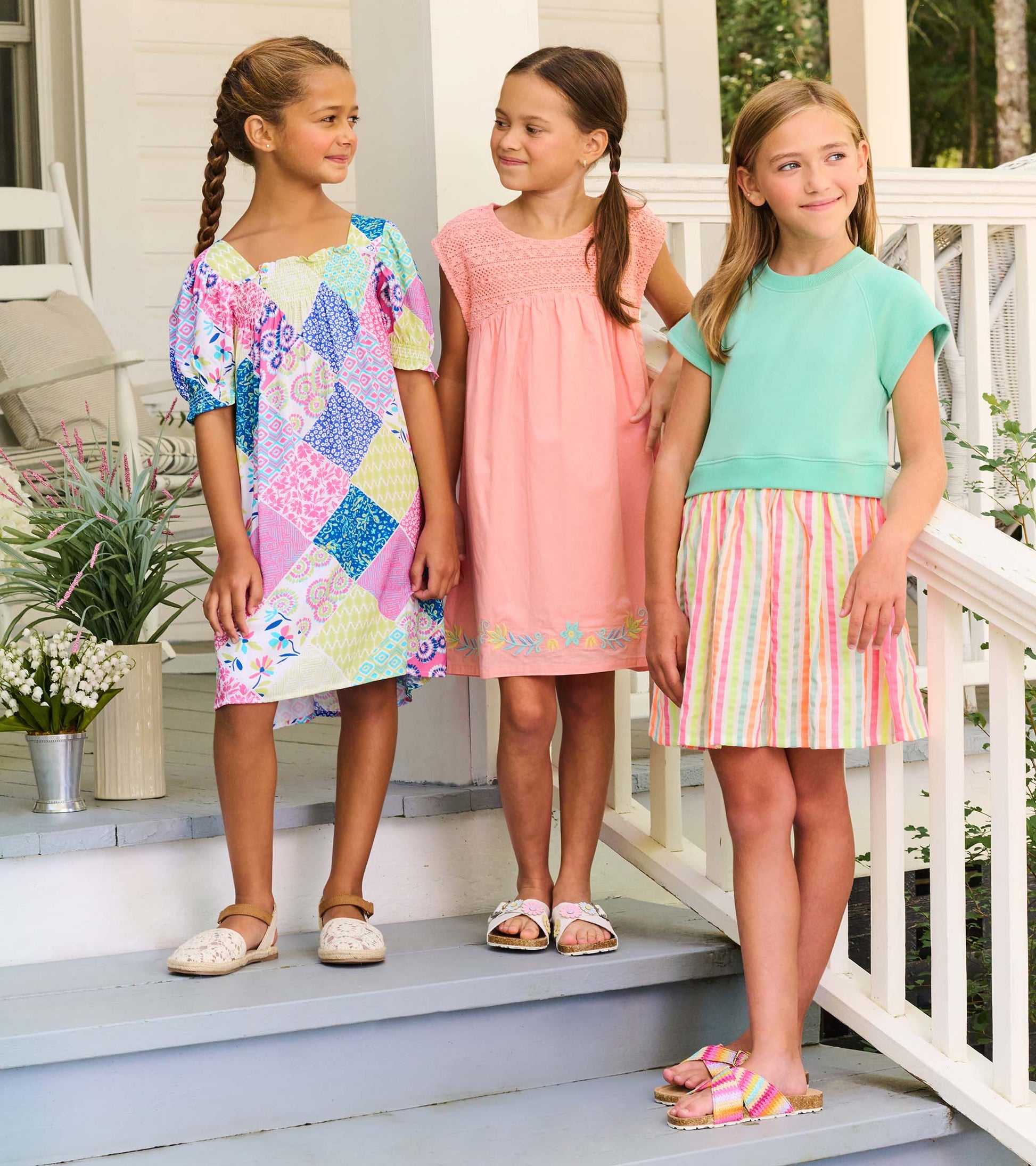 Girls summer dresses in pastel and multicolor prints, shown on three girls standing on porch steps