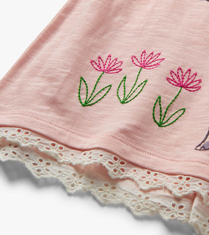 Pink toddler shorts with embroidered flowers and white eyelet lace hem, close-up view
