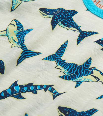 Close-up of white fabric with blue and teal shark print on a boys' raglan T-shirt