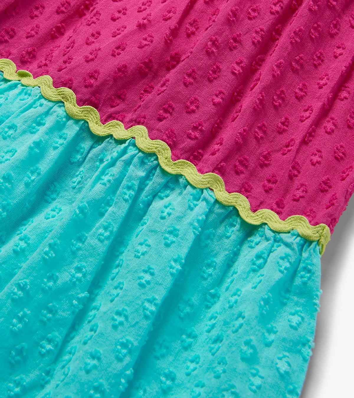 Close-up of pink and turquoise dress tiers with textured fabric and yellow wavy trim
