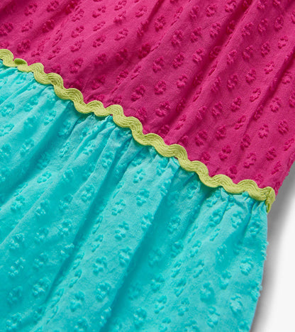 Close-up of pink and turquoise dress tiers with textured fabric and yellow wavy trim