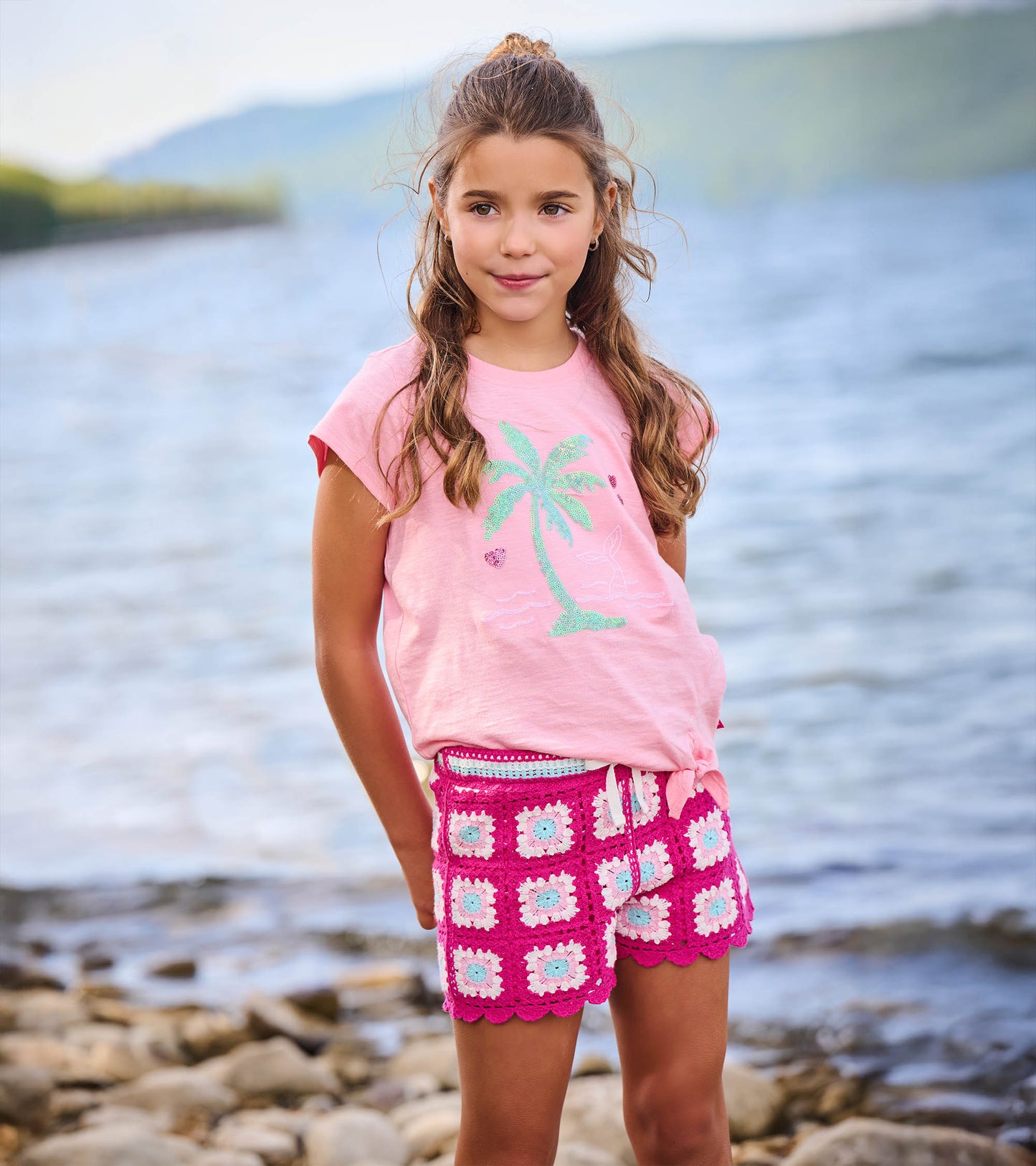 Girls pink crochet shorts with scalloped hem and floral square pattern, front view on model