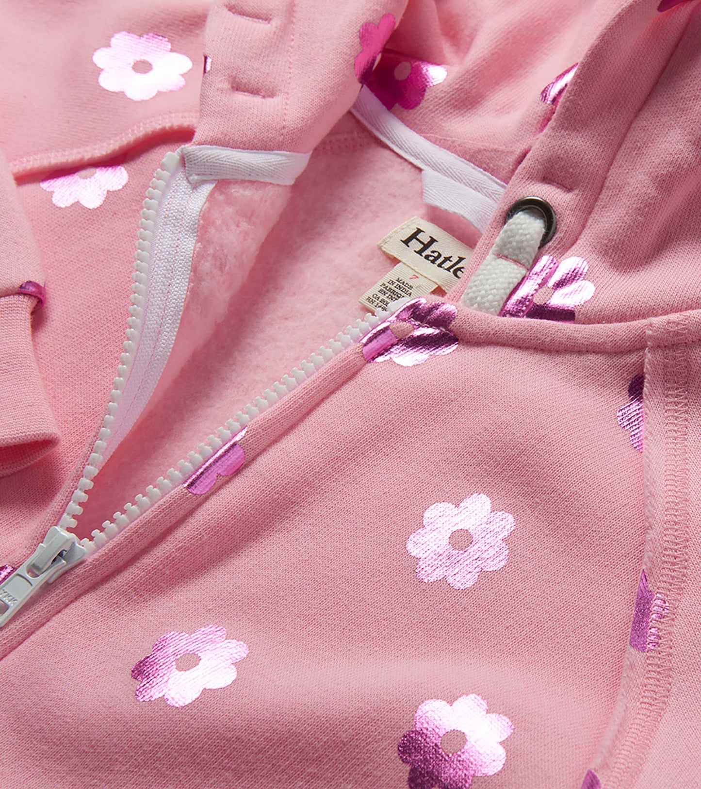 Pink girls zip-up hoodie with metallic flower print and white zipper, close-up front view