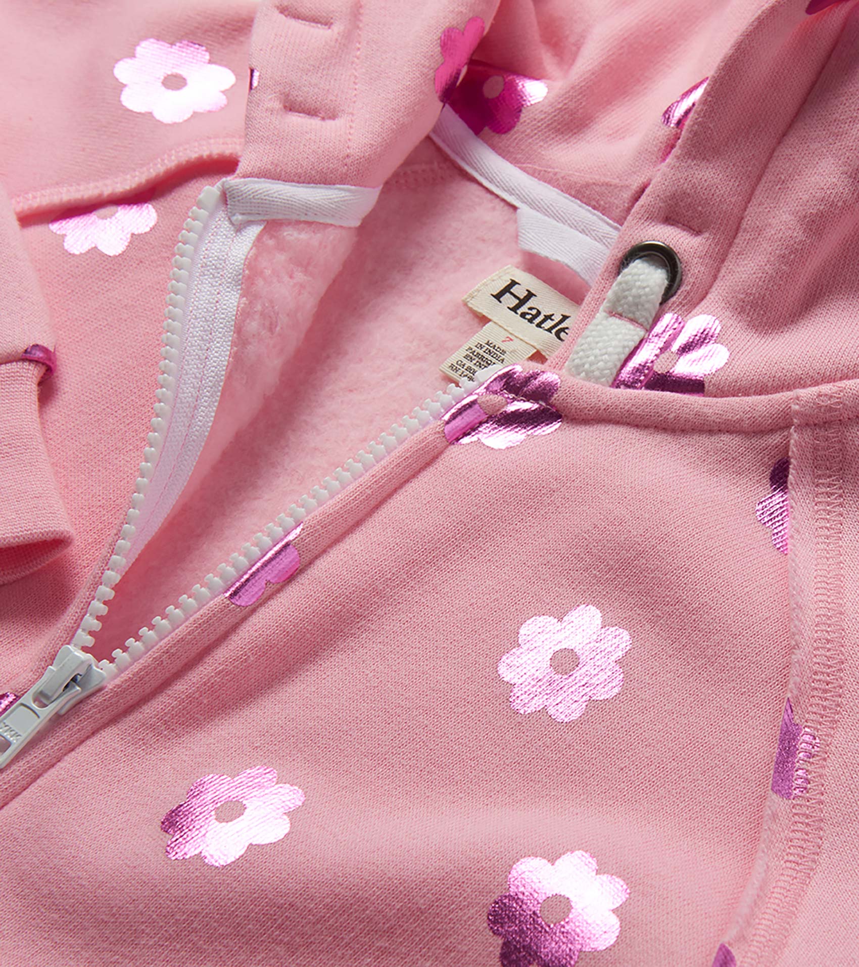 Pink girls zip-up hoodie with metallic flower print and white zipper, close-up front view