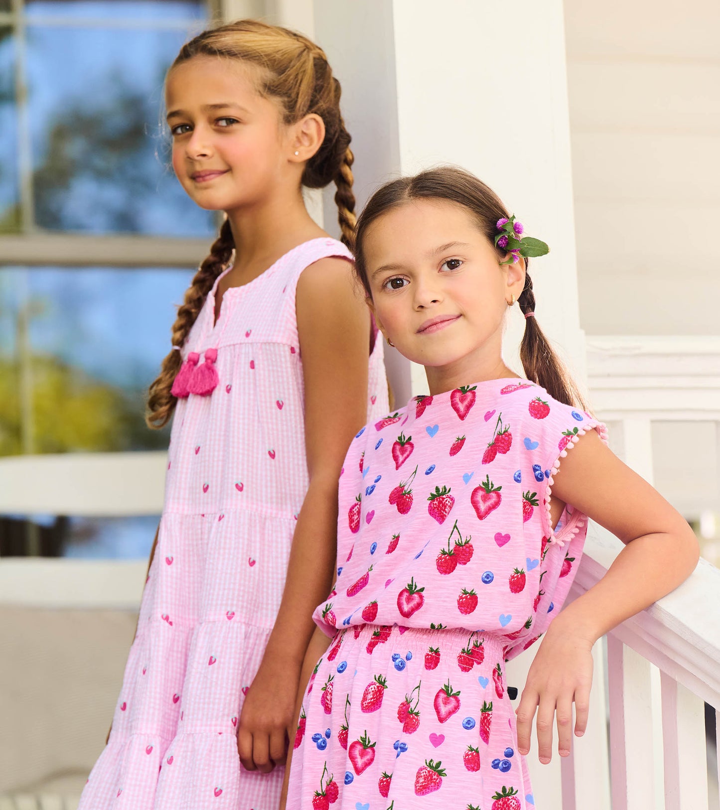 Girls pink berry-print sleeveless dress with smocked waist and pom-pom trim, front view