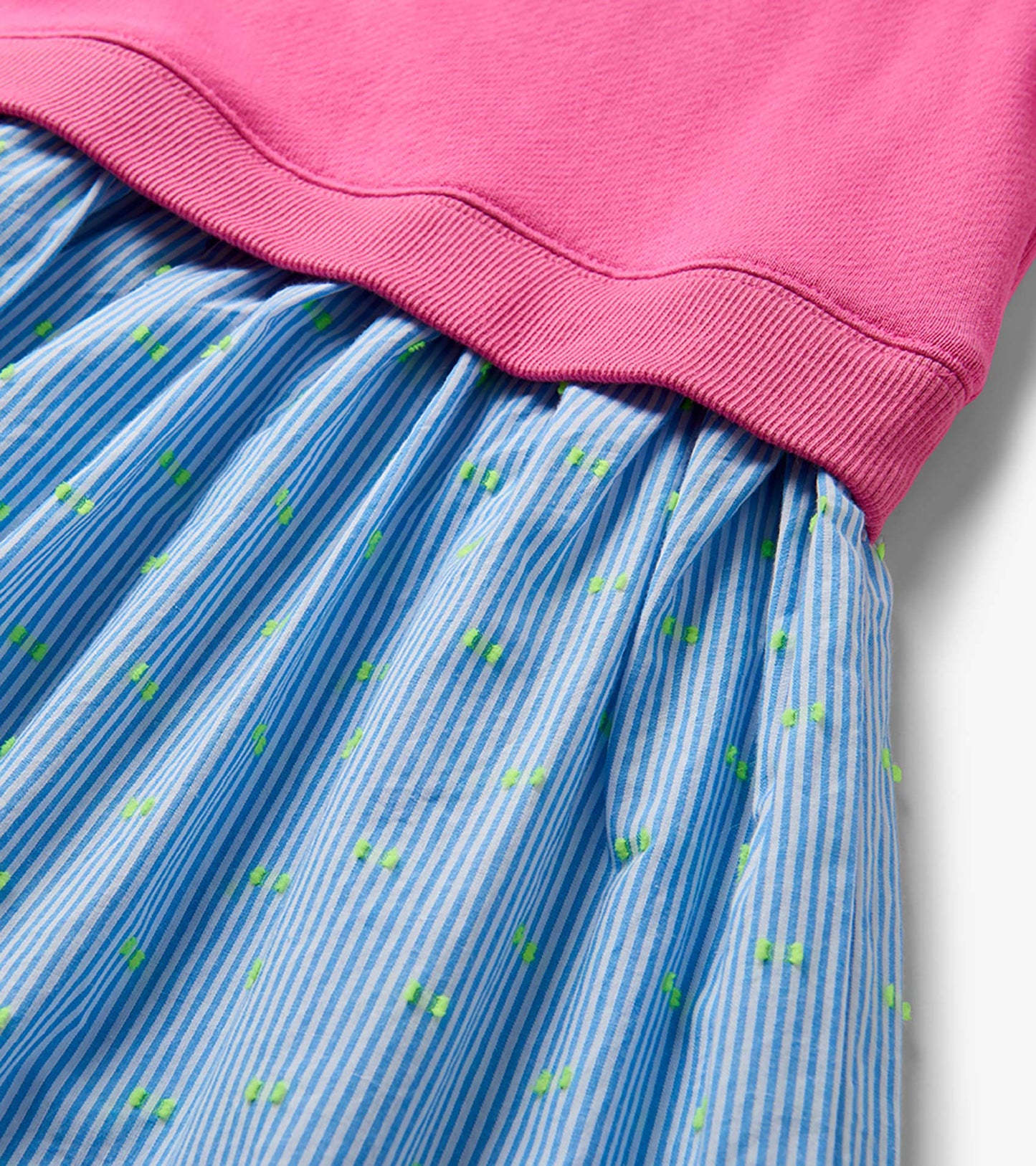 Pink knit top with blue striped skirt and small green strawberry print, close-up view