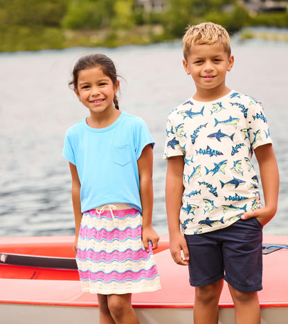 Girls crochet skirt with pink, cream, and blue wavy stripes, shown on a child standing outdoors