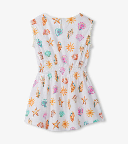 White sleeveless girls dress with colorful seashell and sun print, smocked waist, and flared skirt