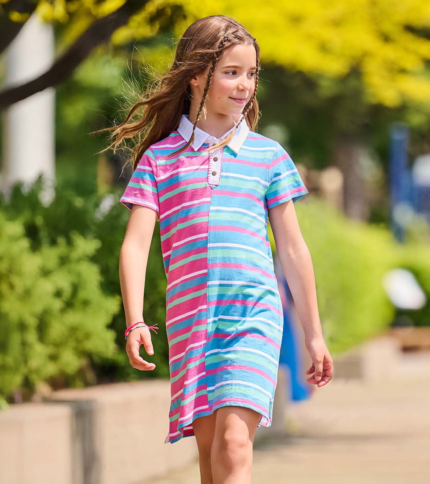 Girl wearing a short-sleeve polo dress with split pink and blue stripes, white collar, and snap placket
