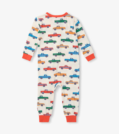 Cream baby sleeper with colorful truck print and orange trim, shown front view