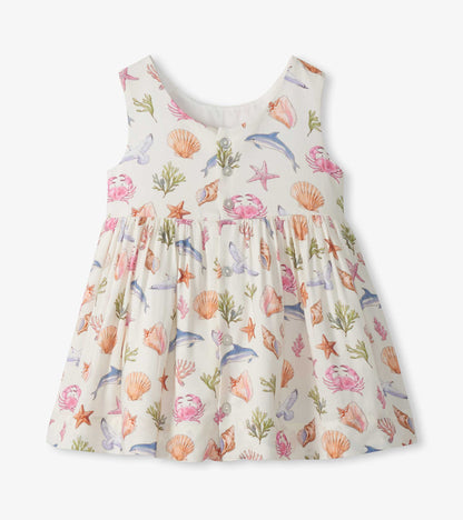 Sleeveless cream toddler dress with colorful sea life print and button-front bodice, front view