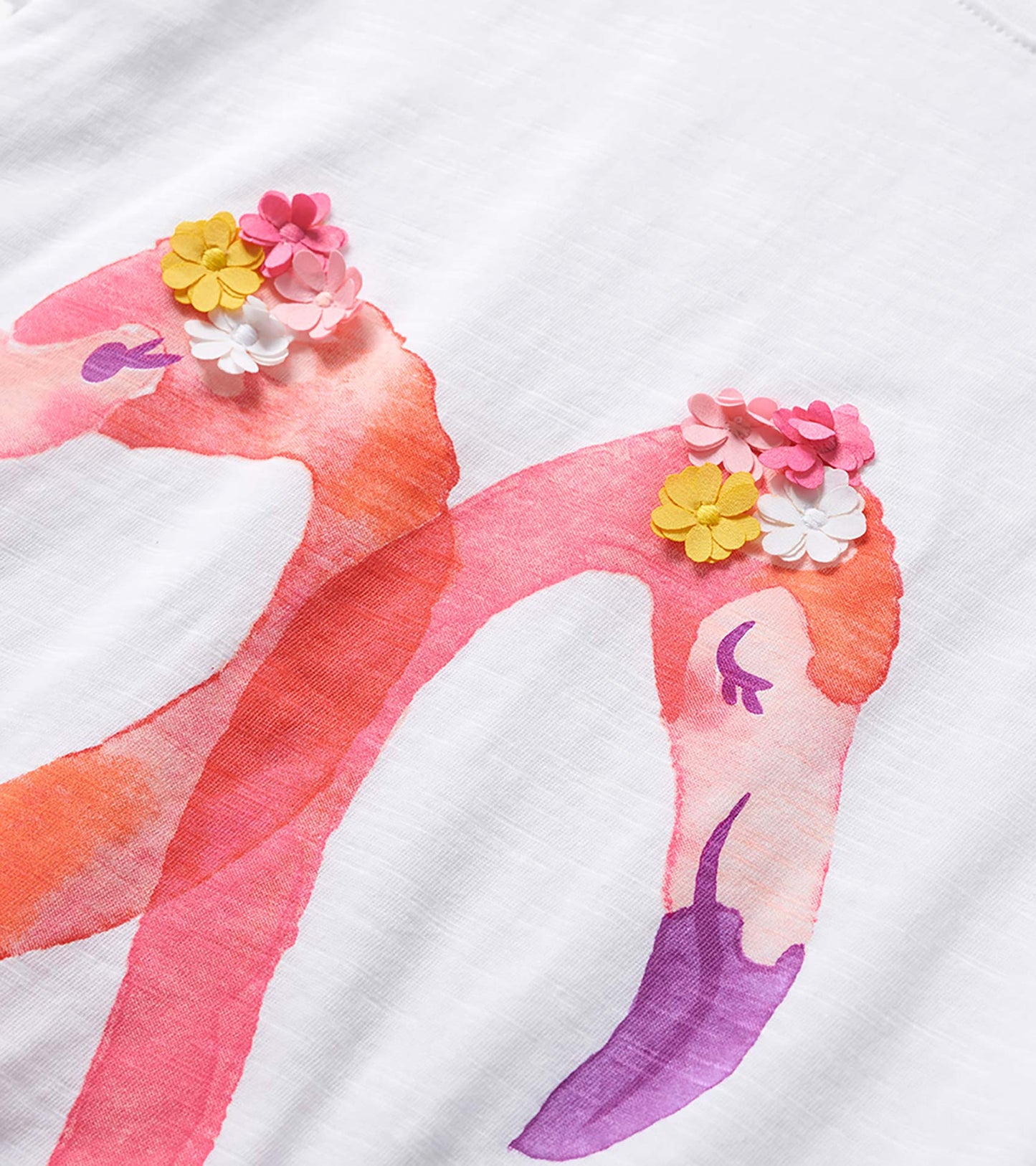White girls' graphic tee with pink flamingos and colorful flower appliqués, close-up front view