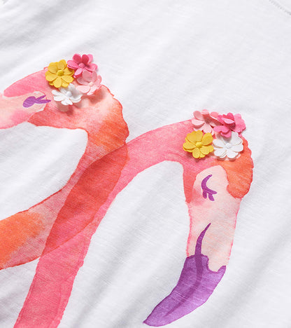 White girls' graphic tee with pink flamingos and colorful flower appliqués, close-up front view