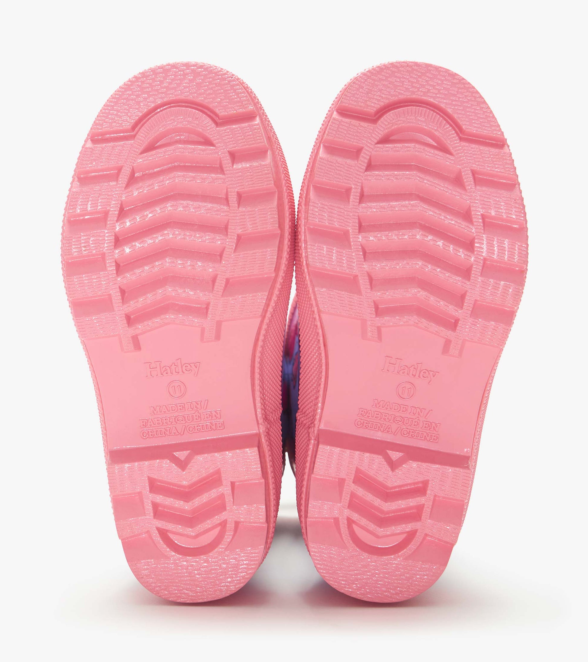 Pink rubber rain boots soles with tread pattern, shown bottom view
