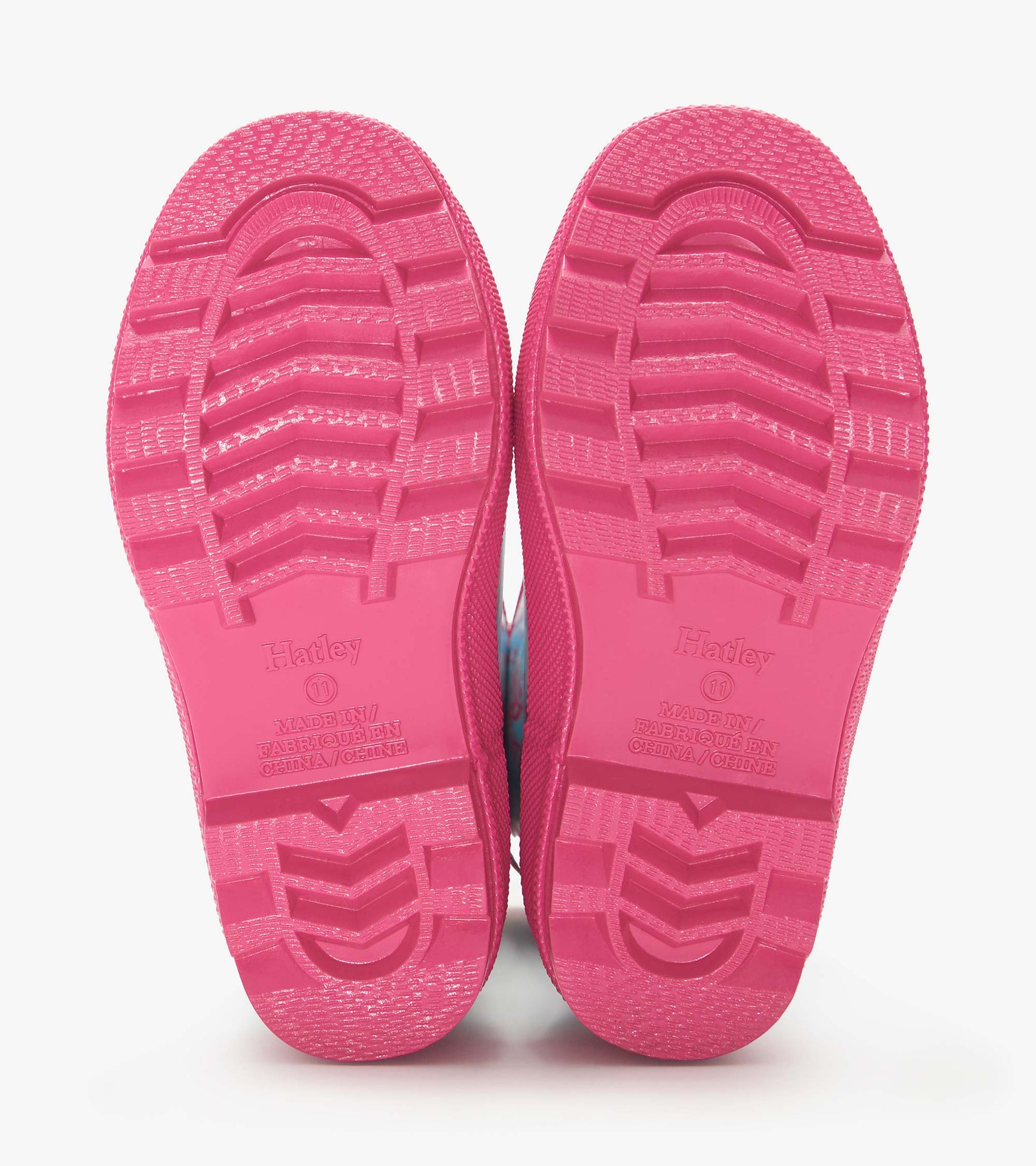 Pair of bright pink rain boots soles with textured tread, shown from the bottom view