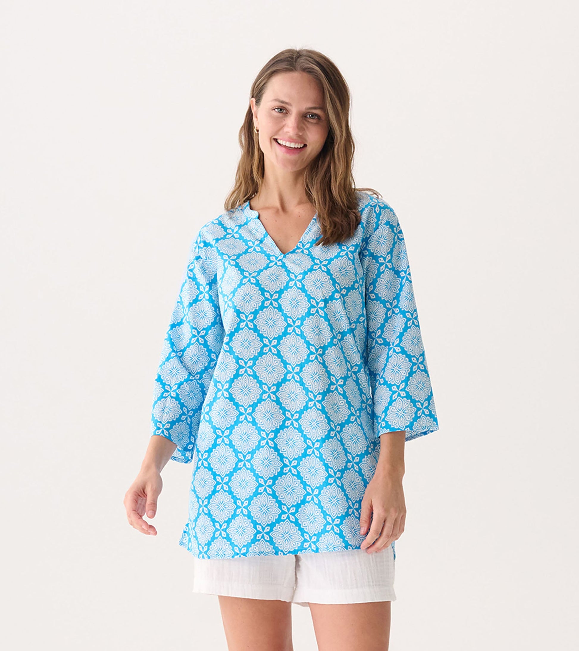Blue tunic with a floral gradient pattern and three-quarter sleeves, featuring a V-neckline and relaxed fit.