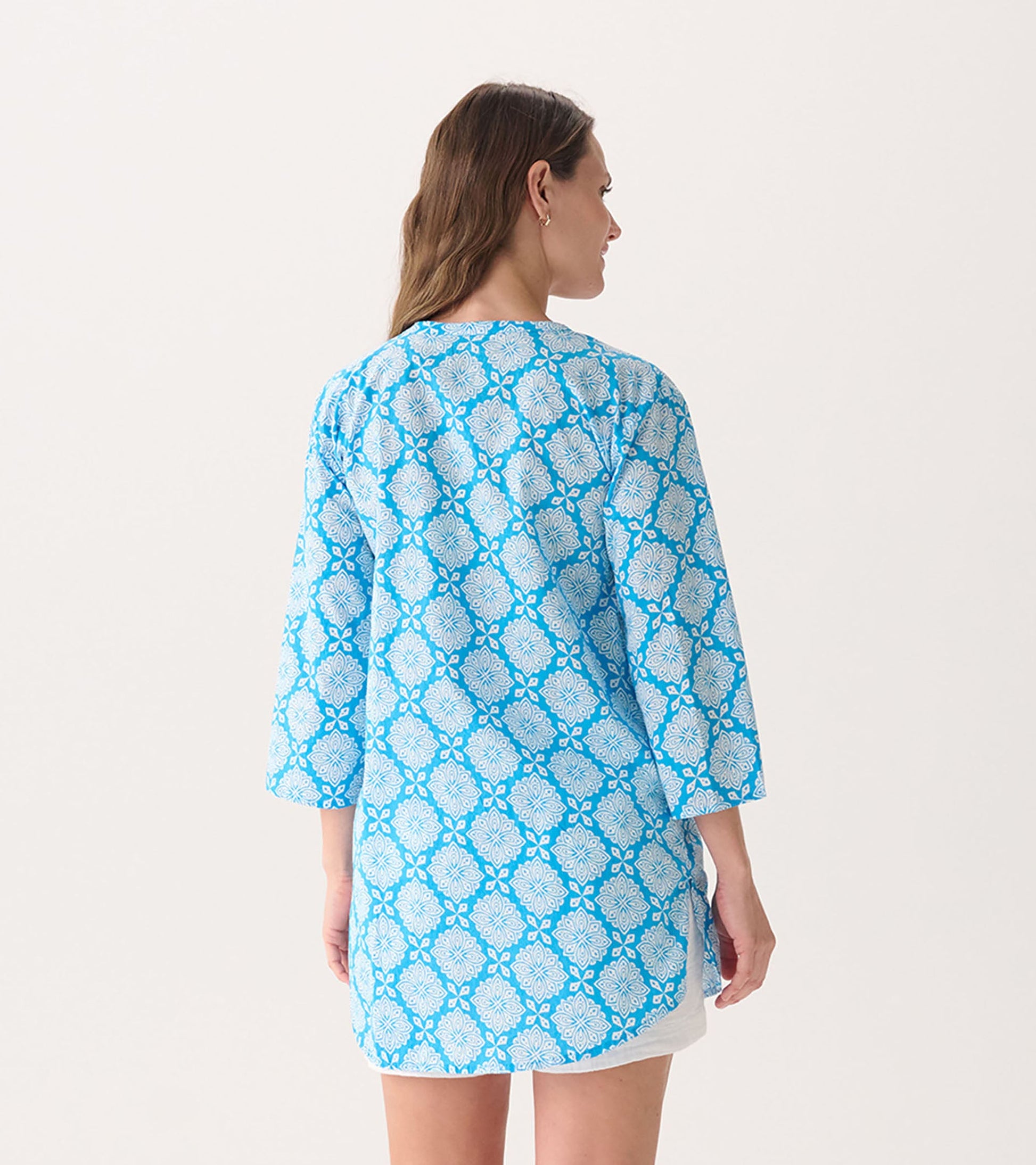 Blue tunic with a gradient floral pattern, featuring three-quarter sleeves and a relaxed fit, shown from the back.