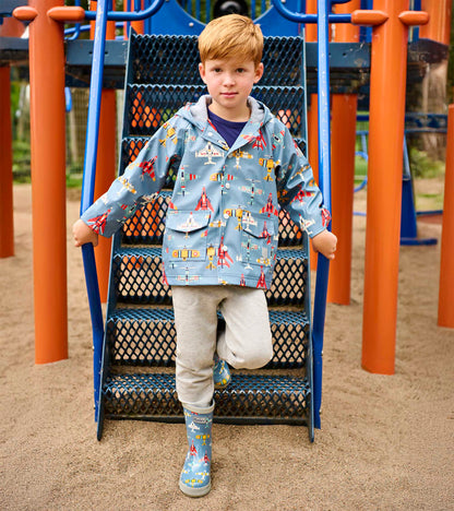 Light blue boys raincoat with airplane print, hood, front pockets, and snap closure, worn by a child outdoors