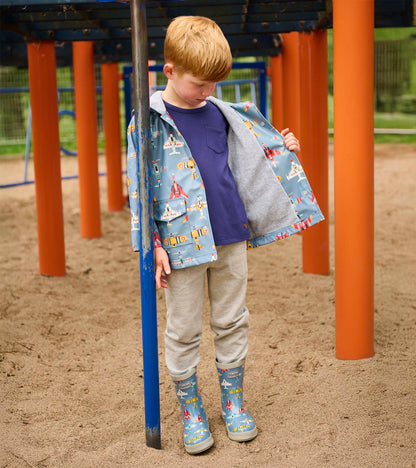 Blue airplane-print kids rain boots on a child standing at a playground