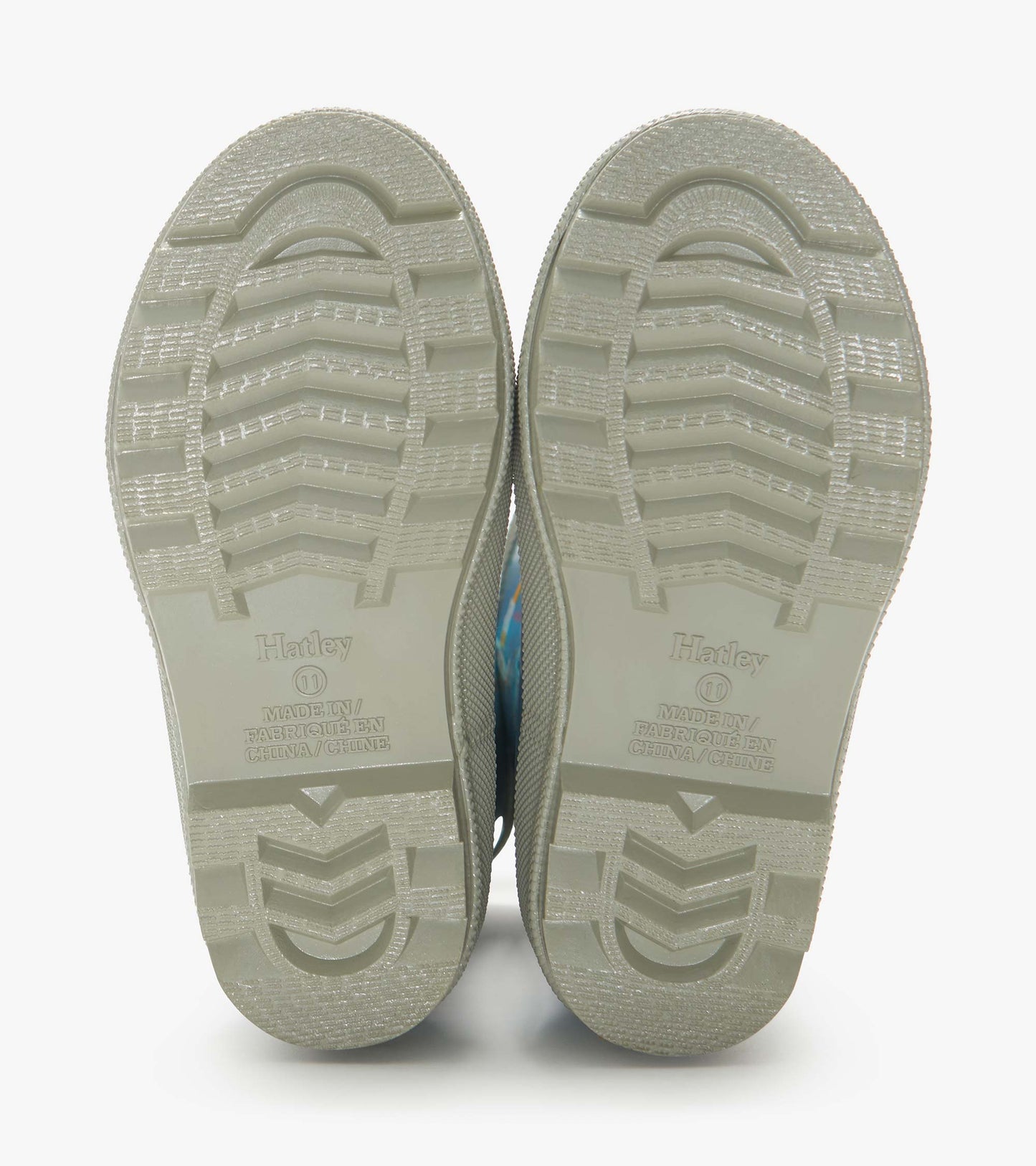 Pair of beige rubber rain boot soles with tread pattern, viewed from below