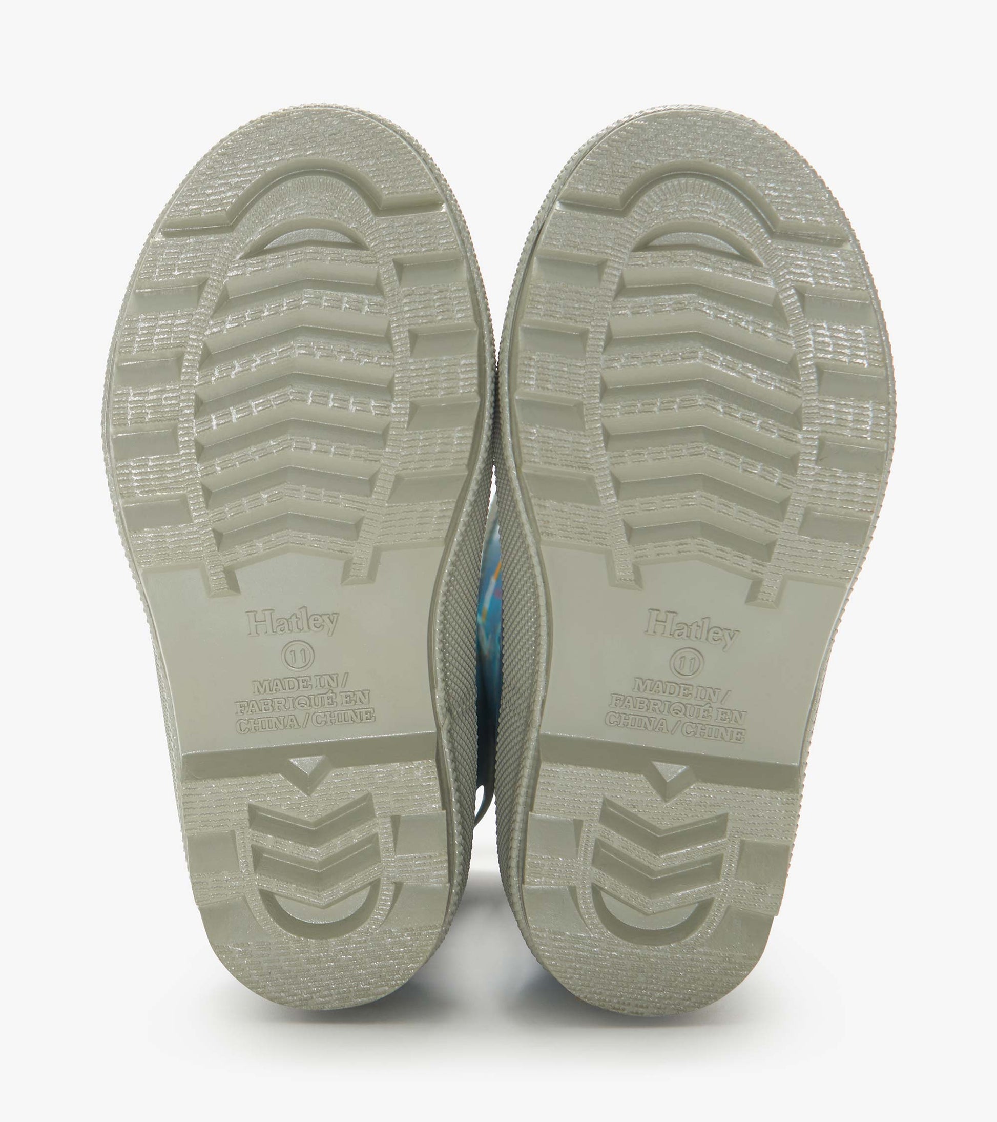 Pair of beige rubber rain boot soles with tread pattern, viewed from below