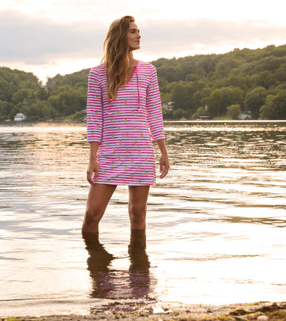 Pink and white striped beach dress with pineapple pattern, featuring a V-neck and three-quarter sleeves, worn by a woman in…