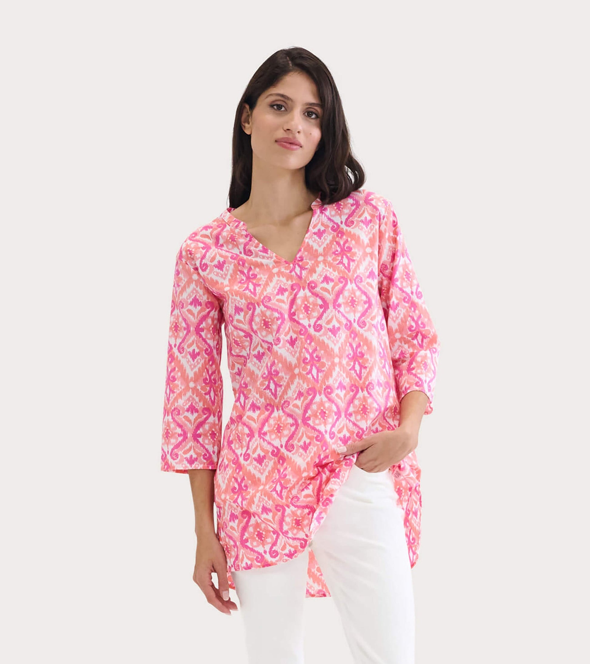 Pink ikat tunic with a V-neck and three-quarter sleeves, styled with white pants.