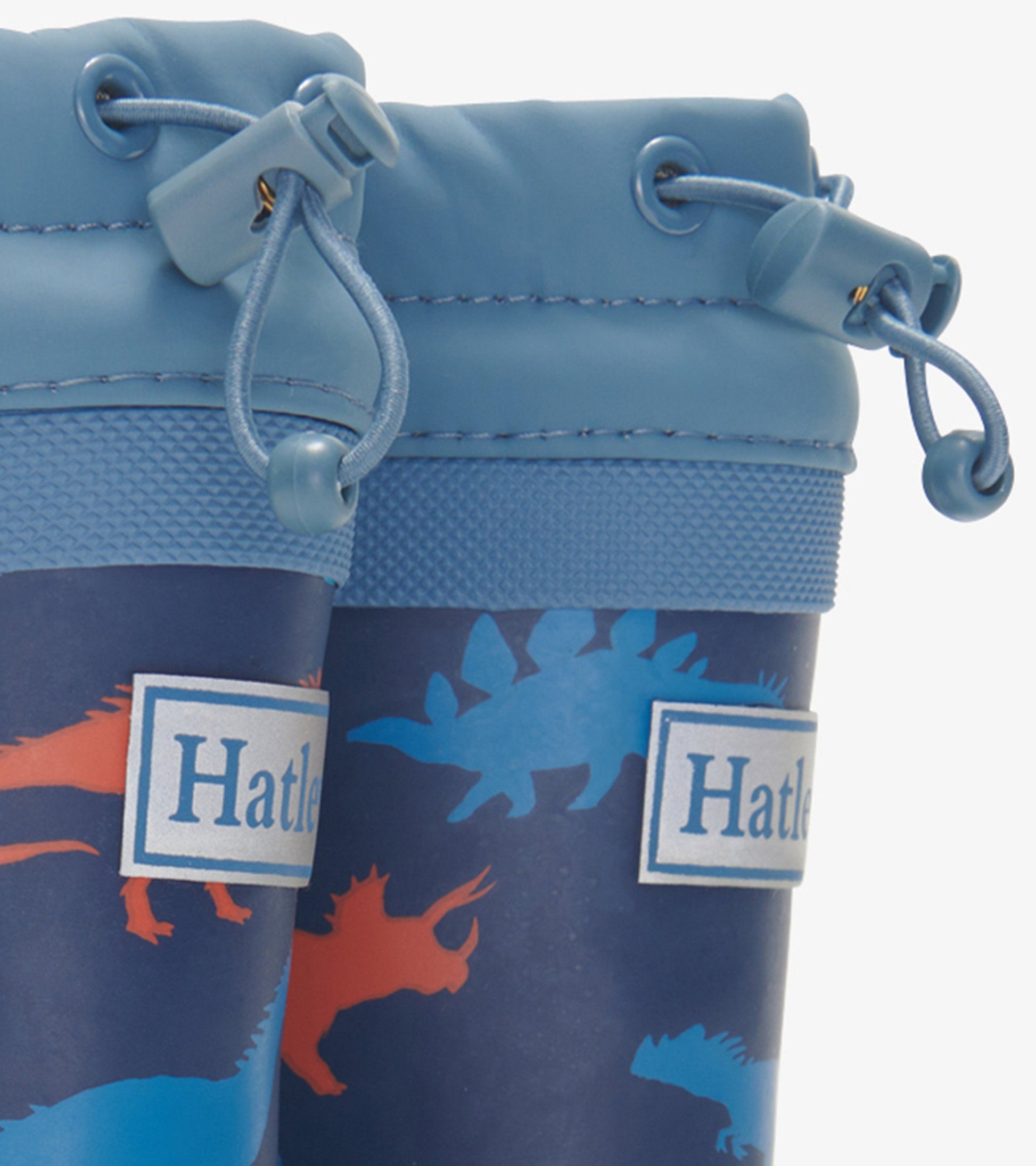 Blue kids' wellies featuring colorful dinosaur silhouettes and a Sherpa lining, with adjustable drawstring tops.